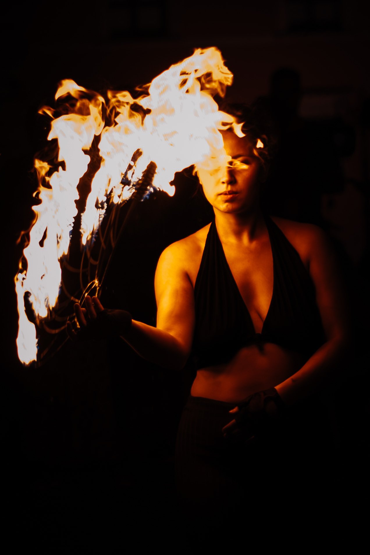 A fire performer holding lit fans at a night time event