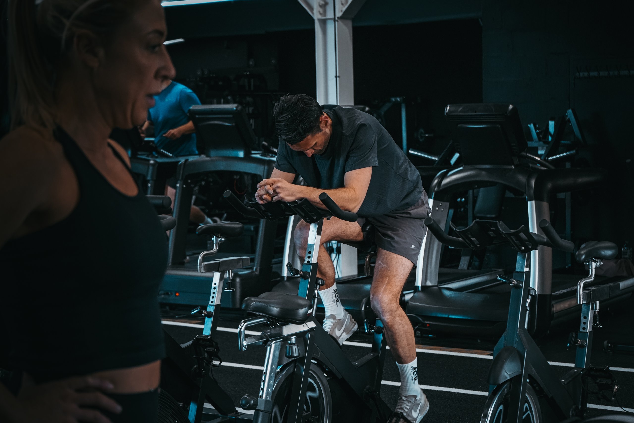 A man riding hard on a spin bike during a studio cycling class