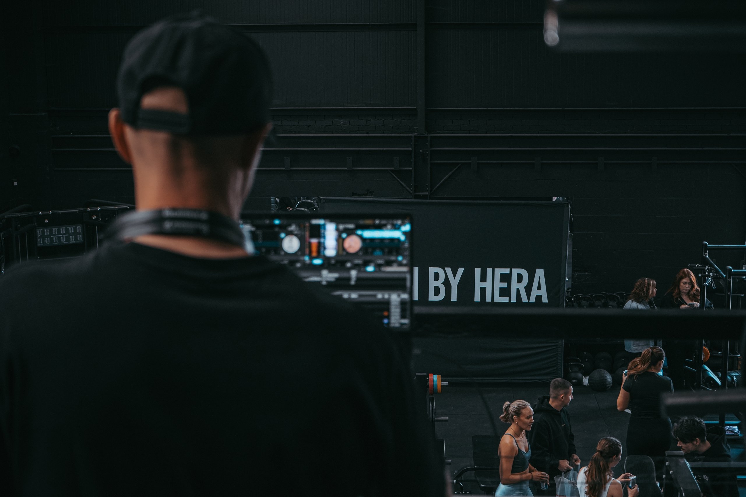 An event crew member at a DJ booth overlooking the floor at a Train By HERA event