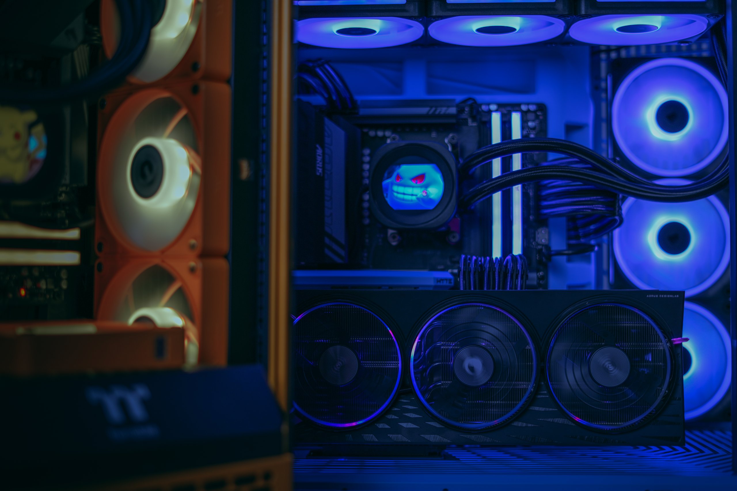 Inside a custom gaming PC, blue and orange lit fans around a graphics card