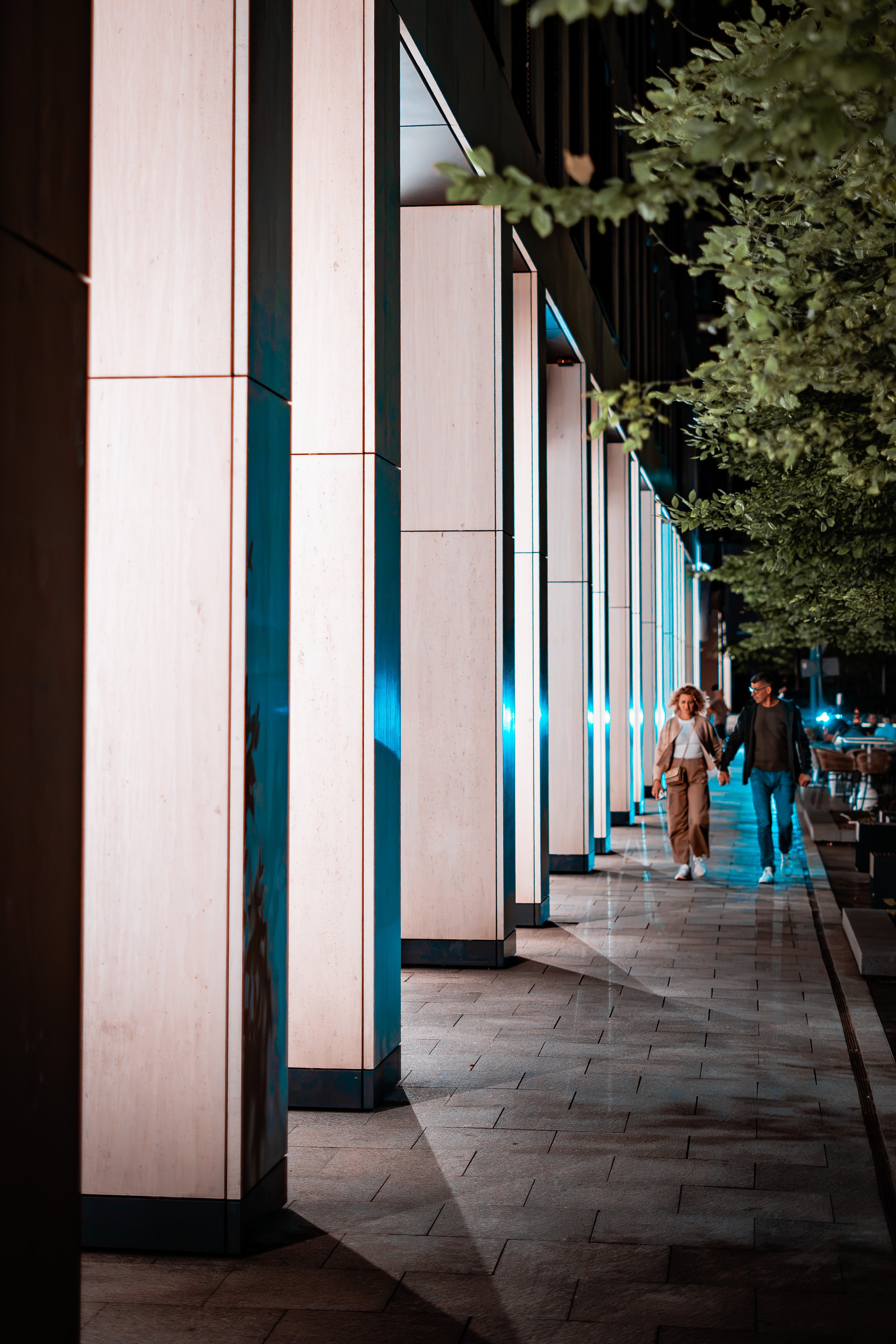 A couple walking past a lit colonnade of stone columns at night