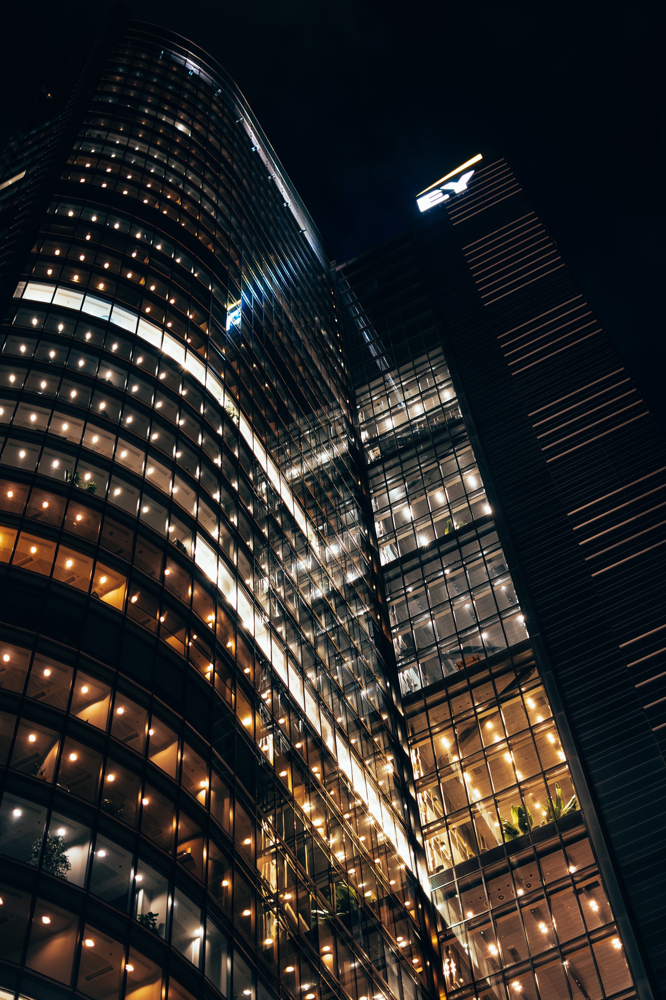 A curved glass office tower lit from within at night