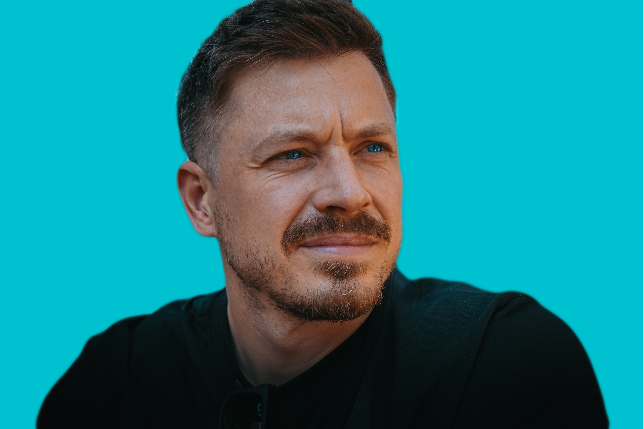 Dom Leigh, commercial photographer, photographed against a bright teal background