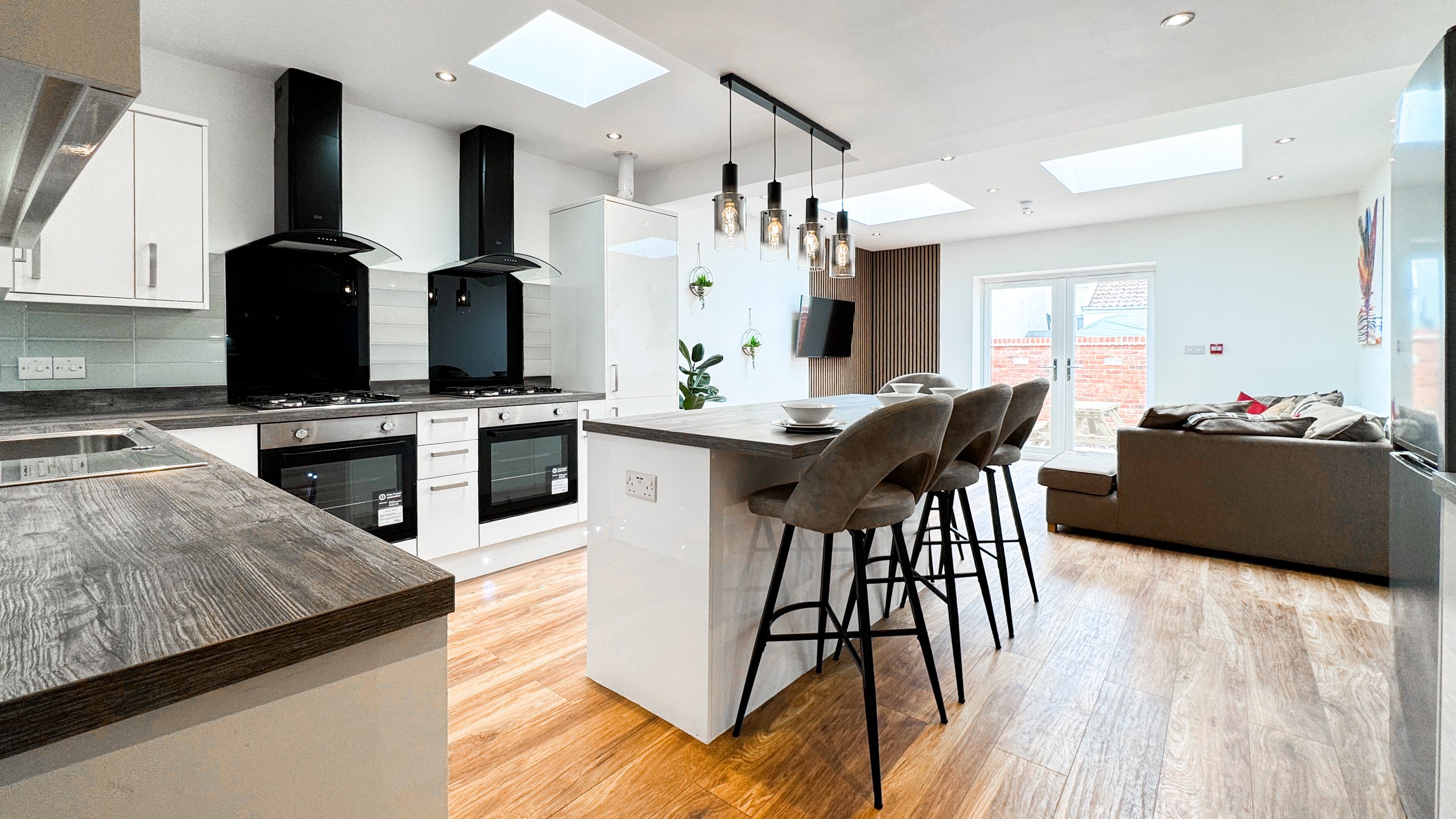 A large open plan kitchen with an island, bar stools and twin skylights