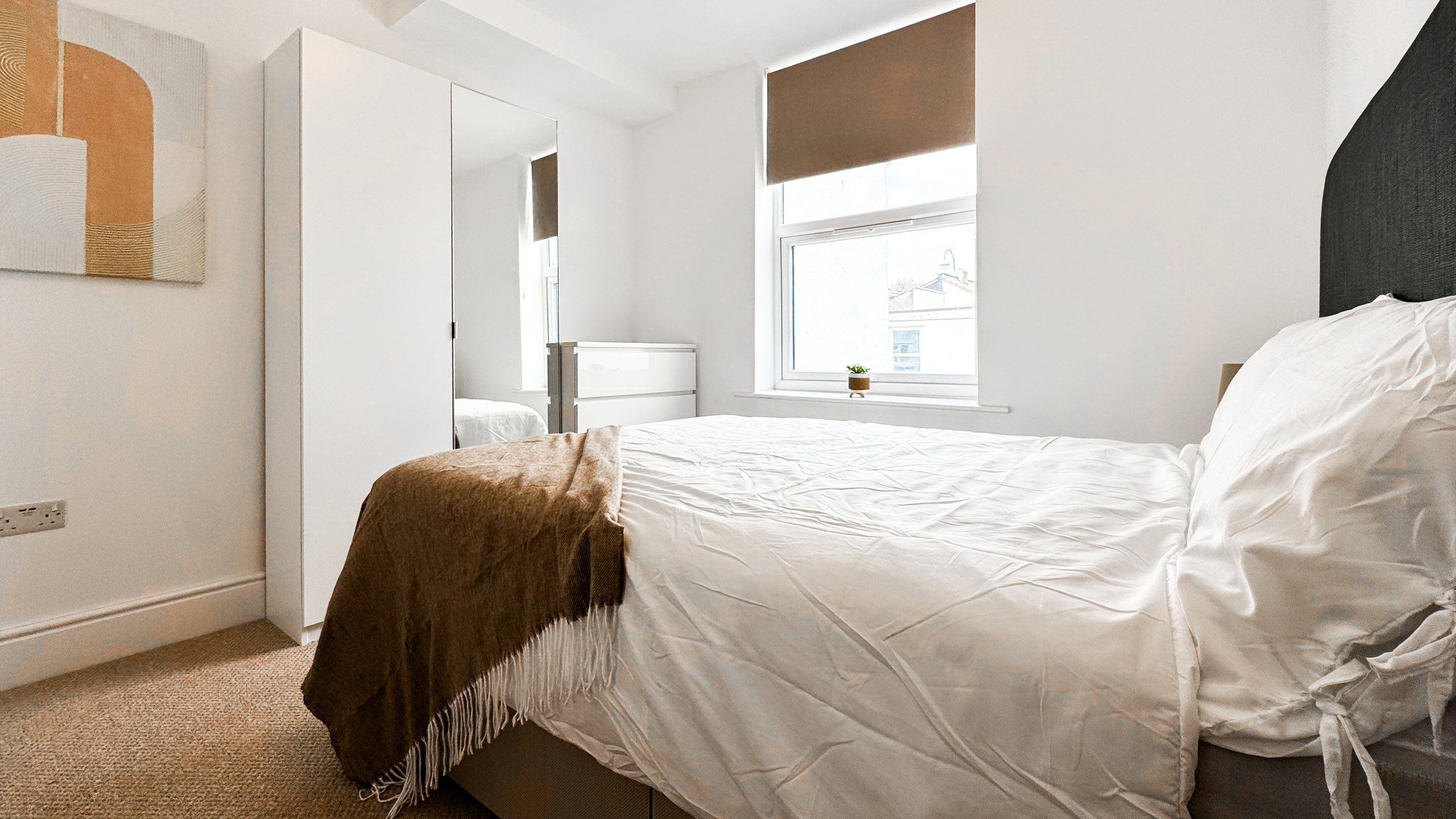 A double bedroom with a mirrored wardrobe and a brown wool throw