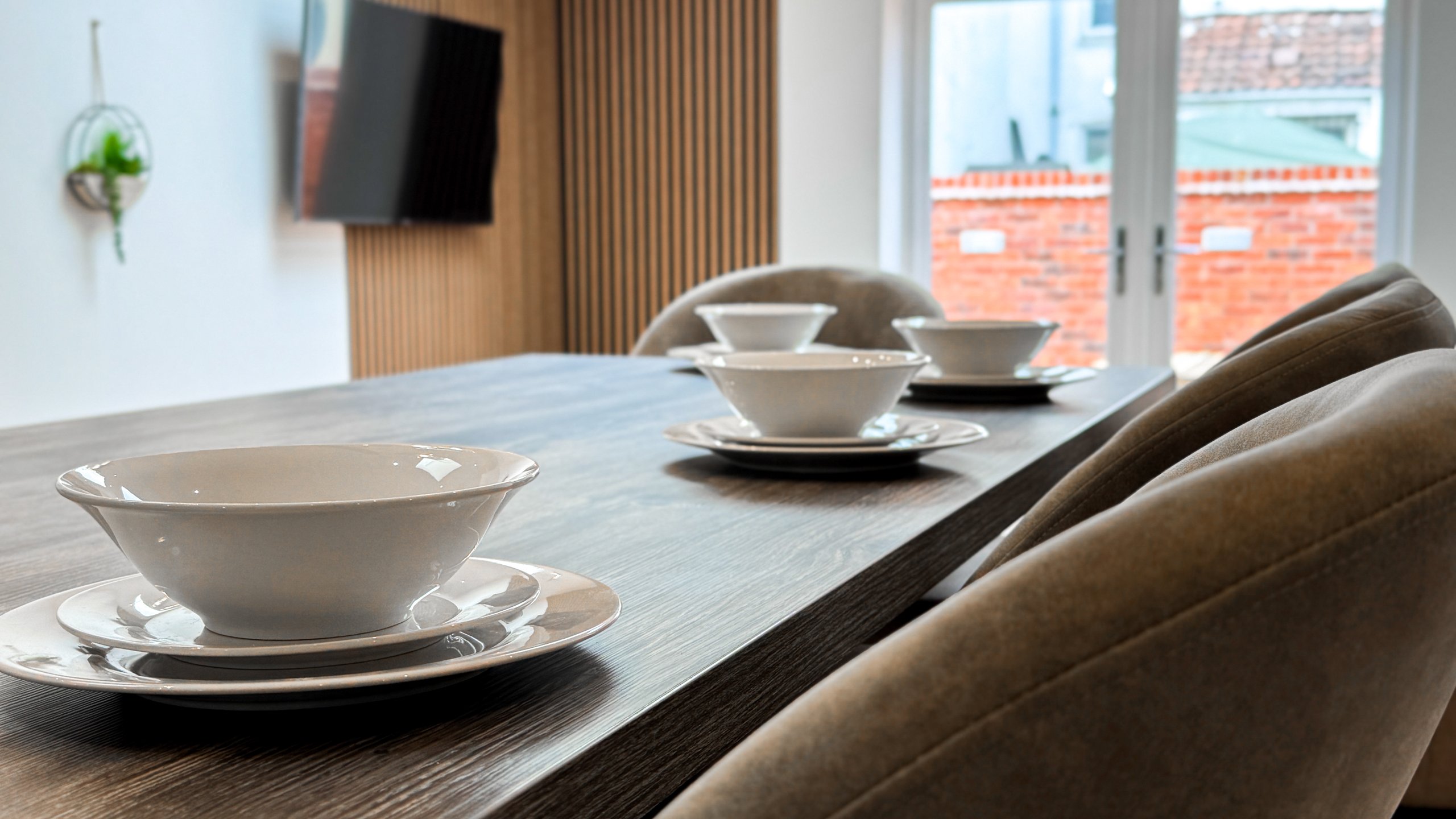 Table settings on a dark wood dining table beside garden doors