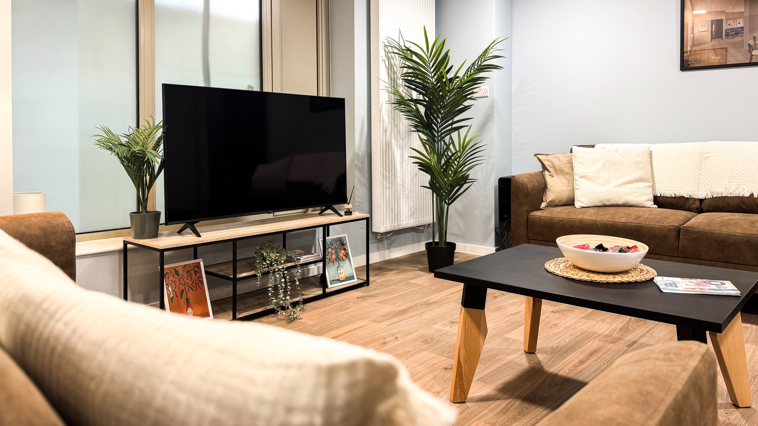 A furnished living room with a television, leather sofa and low coffee table